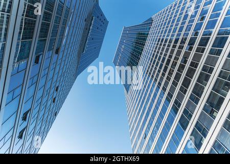 Facciata futuristica di un moderno edificio per uffici rivestito di vetro. Pannelli e finestre in vetro di un edificio moderno. Un edificio per uffici con geometria e Foto Stock