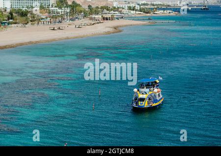 Barche dai colori brillanti sul mare turchese nella costa baia di Eilat Foto Stock