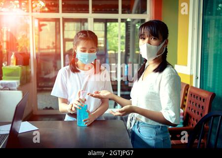 due adolescenti asiatici indossare maschera di protezione viso lavaggio mano da alcool gel Foto Stock