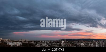 Al tramonto, le nuvole grigie tempestose stanno arrivando alla città sul mare. Panorama di cielo stellato drammatico di sera. Le nuvole di strati scuri si aggrappano a Varna, Bulgaria. Foto Stock