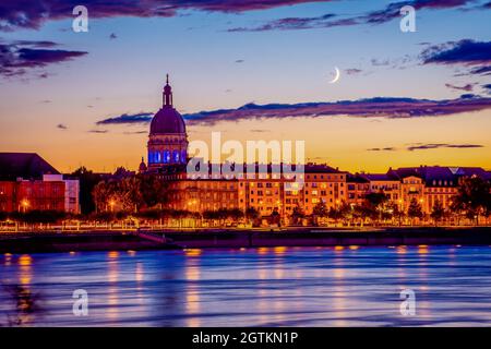 Moonrise e Sunset Lights sopra la Christuskirche a Mainz, nel primo piano del Reno, Germania Foto Stock