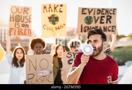 Gruppo di attivisti che protestano per il cambiamento climatico - persone multirazziali che combattono su strada tenendo striscioni su disastri ambientali Foto Stock