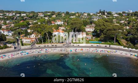 Vista aerea delle tenute costose dietro la spiaggia di Ondes sul Cap d'Antibes nella Costa Azzurra - turisti che prendono il sole sul Mar Mediterraneo nella S Foto Stock