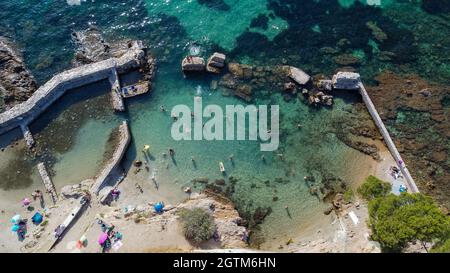 Vista dall'alto di un muro crollato tra Ondes Beach e Mallet Beach sul Cap d'Antibes nella Costa Azzurra - piscina naturale creata dalle rovine di un Foto Stock
