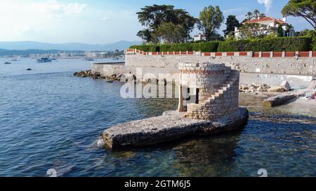 Vista aerea delle rovine di una torre di avvistamento rotonda allagata sul Cap d'Antibes in Costa Azzurra - resti medievali su un piccolo isolotto di Ondes Beach Foto Stock