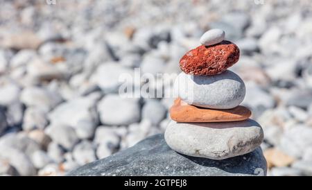 Pietre di equilibrio Zen, torre di roccia liscia impilata su sfondo di spiaggia di ghiaia, giorno di sole. Concetto di armonia e pace, spazio di copia, modello Foto Stock