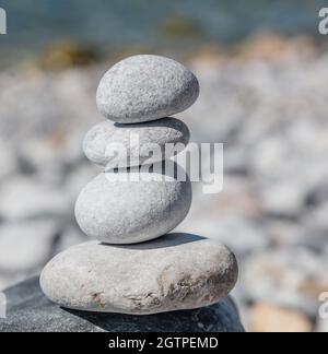 Feng shui, armonia e concetto di pace. Equilibrio, pietre zen, torre di roccia liscia impilata su spiaggia di ciottoli, sfondo blu mare, giorno di sole. Foto Stock