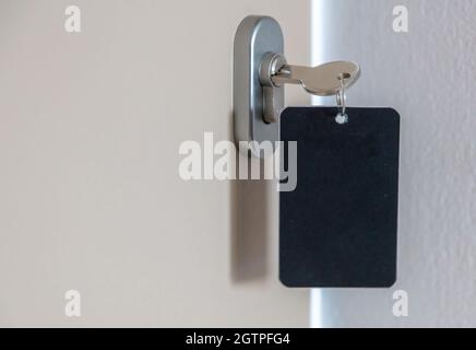 Chiave porta con etichetta vuota nel foro. Portachiavi in acciaio, chiave ambiente e etichetta nera vuota per la visualizzazione ravvicinata di testo o numeri. Camera di casa, hotel o motel op Foto Stock