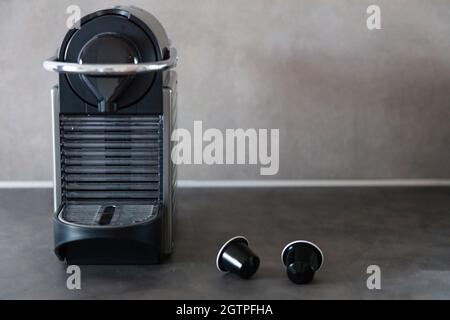 Macchina da caffè per espresso con cialde. Macchina e capsule di colore nero sul tavolo della cucina domestica, vista frontale, spazio copia, modello Foto Stock