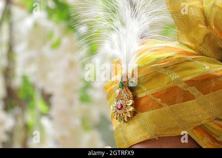 Immagina una scena vivace sotto un mandap splendidamente decorato, dove la coppia felice si siede fianco a fianco, irradiando gioia. La sposa, riccamente adornata Foto Stock