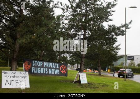 Farnborough, Regno Unito. 2 ottobre 2021. Un banner e segni sono esposti dagli attivisti climatici della Rebellion d'estinzione all'esterno di un ingresso all'Aeroporto di Farnborough. Gli attivisti hanno bloccato tre ingressi all'aeroporto privato per evidenziare livelli elevati di anidride carbonica prodotti dai passeggeri super ricchi che utilizzano jet privati e il lavaggio del verde da parte dell'aeroporto, annunciando il passaggio al carburante per aviazione sostenibile (SAF). Credit: Mark Kerrison/Alamy Live News Foto Stock