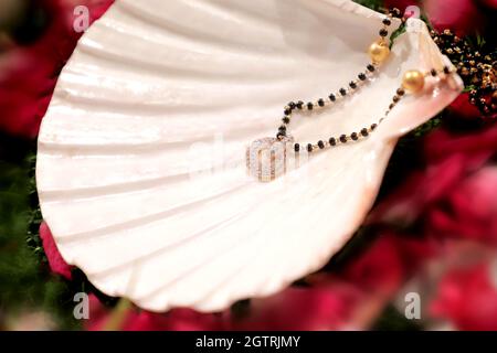 Immagina una scena vivace sotto un mandap splendidamente decorato, dove la coppia felice si siede fianco a fianco, irradiando gioia. La sposa, riccamente adornata Foto Stock