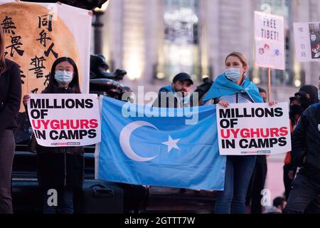 Colombe Cahen-Salvador (R), attivista per i diritti umani, è stato visto tenere la bandiera del Turkestan orientale, insieme al segno che dice 'migliaia di uiguri in Camps' durante la manifestazione. Il 1° ottobre, varie diaspore anti-Cina a Londra si sono riunite in solidarietà contro il Partito comunista cinese. Tenuto congiuntamente da Hong Kong Liberty, World Uyghur Congress, Free Tibet e altri, a Piccadilly Circus sono stati tenuti discorsi per condannare le violazioni dei diritti umani da parte del PCC. I manifestanti in seguito marciarono presso l'Ambasciata cinese a Londra, dove venne bruciata la Bandiera Nazionale Cinese. Foto Stock