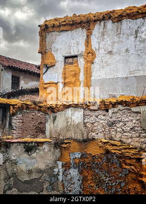 una demolizione di una vecchia casa in un quartiere storico, con pareti con schiuma di poliuretano giallo o ocra e pareti in mattoni deteriorati, verticale Foto Stock