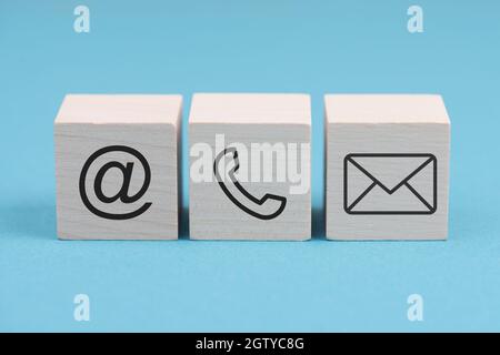 Segni per e-mail, telefono e newsletter su blocchi di legno, sfondo blu, simboli e segni Foto Stock