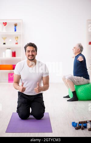 Giovane istruttore e vecchio che fa esercizi sportivi Foto Stock