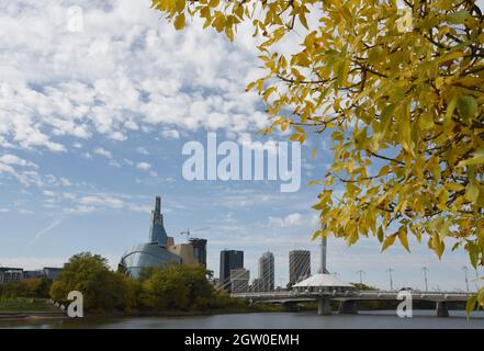 Il fogliame autunnale e lo skyline di Winnipeg, Manitoba, Canada, con il Canadian Museum of Human Rights (al centro a sinistra) e il ponte pedonale Esplanade Riel Foto Stock