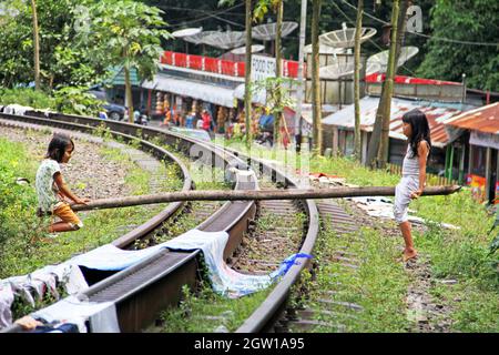 Due giovani ragazze che giocano su vecchi binari del treno usando un vecchio palo di legno come una sega a vista improvvisata a Lembah Anai, Sumatra Occidentale, Indonesia. Foto Stock