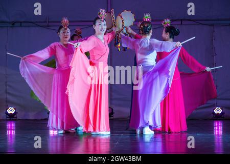 Un gruppo di donne coreane in abiti tradizionali hanbok, ballando sul palco con sogo (batteria a mano) Foto Stock