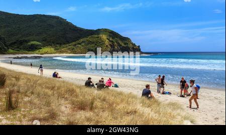 La spiaggia di Tapotupotu Bay, Northland, Nuova Zelanda, con un gruppo di turisti che si godono il sole estivo Foto Stock