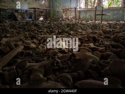 Maschere di gas sul pavimento della scuola del distretto 3 - Pripyat, zona di esclusione di Chernobyl, Ucraina Foto Stock