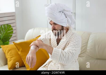 Un giovane uomo strofina la crema mano nelle sue mani asciutta dall'inverno Foto Stock