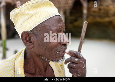 shepard africano invecchiato camminando sulla spiaggia tenendo bastone Foto Stock