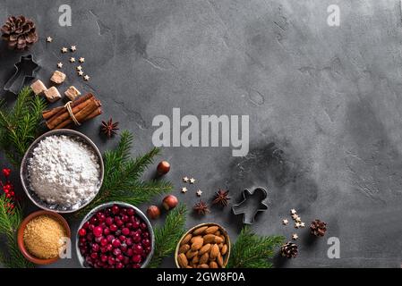 Sfondo della cottura natalizia con cramberris, noci, ingredienti alimentari e spezie di stagione. Cucinare i biscotti natalizi stagionali per le vacanze invernali Foto Stock