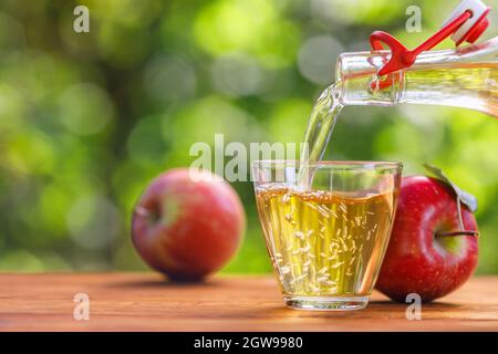 sidro di mele o succo versando in vetro dal flacone Foto Stock