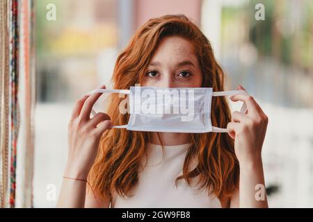 Giovane donna con capelli di rea con maschera medica, protezione e precauzioni per le malattie contagiose. Interruzione del virus Corona. Foto di alta qualità Foto Stock