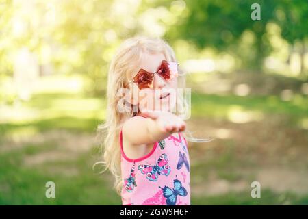 Giovane ragazza in posa in Fancy Pink a forma di pentagonale occhiali da  sole all'aperto. Carino adorabile Child elegante Foto stock - Alamy