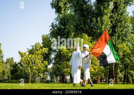 immagine cinematografica di una famiglia degli emirates che trascorre del tempo al parco. Giovane che gioca a calcio in erba Foto Stock