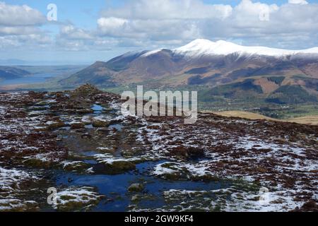 La catena montuosa 'Skiddaw' nella neve da un pile di pietre vicino alla cima del Wainwright 'Bleaberry Fell' nel Lake District National Park. Foto Stock