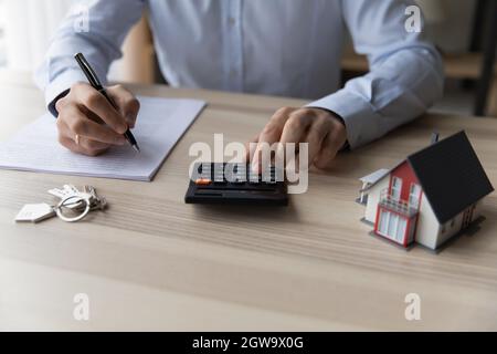 Realtor businessman usando calcolatore, seduto alla scrivania con mockup casa Foto Stock
