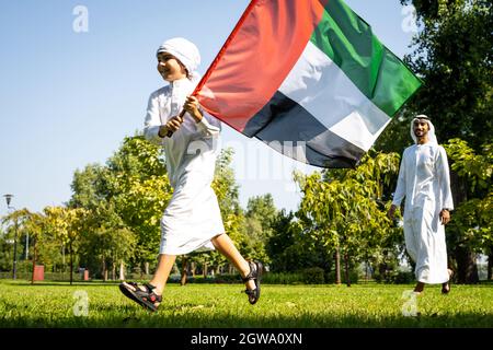 immagine cinematografica di una famiglia degli emirates che trascorre del tempo al parco. Giovane che gioca a calcio in erba Foto Stock