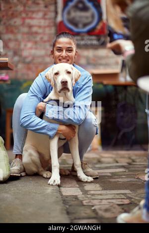 ritratto di una bella giovane donna caucasica abbracciando il suo cane, sorridente Foto Stock