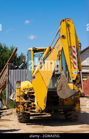 Un vecchio escavatore giallo grungy in un'area di costruzione Foto Stock