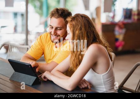 Una coppia di amici o colleghi che si siedono in un bar e che guardano un tablet. Foto di alta qualità Foto Stock