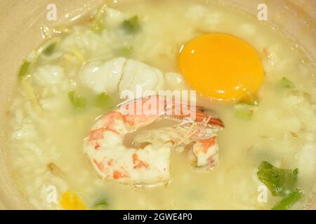 gamberetti di porridge di riso e calamari con tuorlo d'uovo con aggiunta di zenzero sulla ciotola Foto Stock