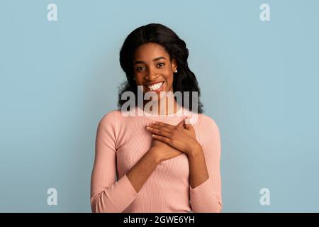 Concetto di gratitudine. Grazie African American Female mantenendo entrambe le palme sul torace, la Donna Nera riconoscente che esprime apprezzamento e gentilezza mentre si levano in piedi Foto Stock