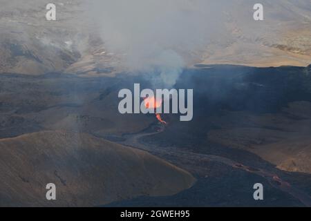 Il campo di lava a Fagradalfjall, Islanda. Bocca attiva con eruzione di lava fusa e aumento di gas vulcanico. Lava nera e cielo blu. Immagine aerea. Foto Stock