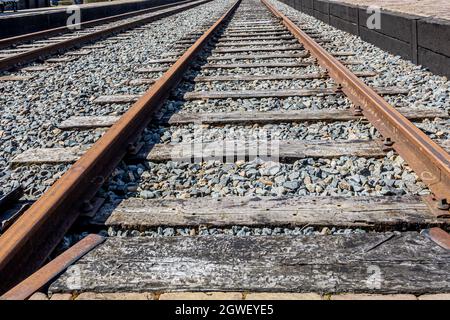 Primo piano di una ferrovia con le sue rotaie arrugginite e traversine di legno tra la ghiaia, giorno di sole a Medemblik a Noord-Holland, Paesi Bassi Foto Stock