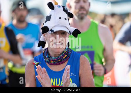 Londra, Inghilterra. 3 ottobre 2021. Una signora si aggrappa mentre corre indossando un cappello di mucca durante la London Marathon 2021 al Tower Bridge di Londra, Inghilterra. Credit: SMPNEWS / Alamy Live News Foto Stock