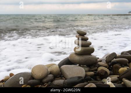 Piramide equilibrante di pietre di mare su una spiaggia di ciottoli Foto Stock