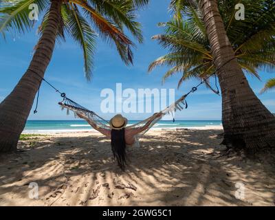 Phuket Thailandia. Giovane donna asiatica che si rilassa sull'amaca vicino alla spiaggia al tramonto. Giovane attraente femmina che oscilla su amaca. Vacanza estate Foto Stock