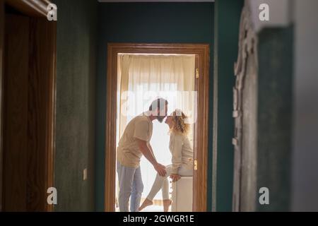 Una coppia amorevole si bacia a casa. Profilo di coppia affettuosa baciare in casa d'appartamento. Uomo e donna romantici baciare all'interno della domesti Foto Stock