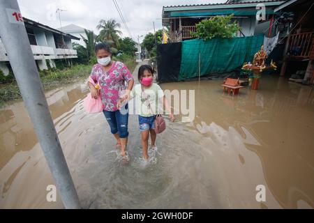 I residenti guado attraverso una strada sommersa come acqua trabocca dal fiume Chao Phraya nella provincia di Pathum Thani. L'influenza della tempesta di Dianmu che colpisce il paese ha aumentato i timori che la mega-inondazione che ha colpito il bacino del fiume Chao Phraya 10 anni fa si ripeterà. Questo disastro ha causato danni per oltre 100 miliardi di baht. Anche se molti esperti di acqua sono venuti fuori per dissipare i timori, dicendo che il volume di acqua nel bacino di fiume è molto meno quest'anno rispetto alla grande inondazione nel 2011, ci sono tuttavia molte somiglianze. Foto Stock