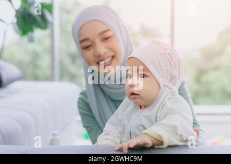 Musulmana Madre guardare il suo bambino felice sorridente infante casa cura insieme carino bella infanzia indoor. Foto Stock