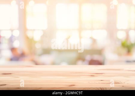 Piano tavolo in legno in primo piano con negozio di caffè interno sfocato e sfondo ristorante per i prodotti mostra banner pubblicitari montaggio. Foto Stock