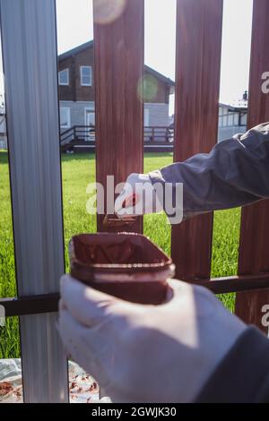 Un uomo dipinge una recinzione in ferro nel giardino Foto Stock